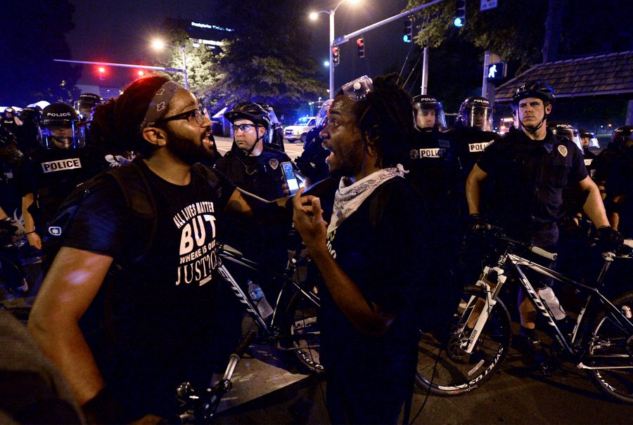 Protesters talk with one another as Charlotte-Mecklenburg police officers monitor the march at Queens Road Sunday, Sept. 25, 2016 in Charlotte, N.C. (Jeff Siner/Charlotte Observer/TNS)