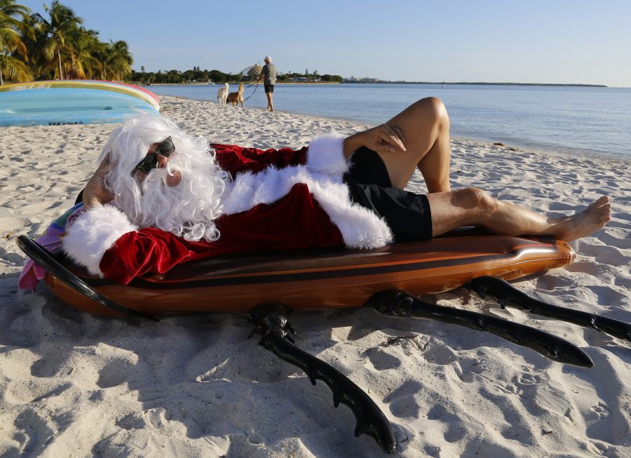 Dave Santa Claus Barry finds the perfect beach spot for his Giant Cockroach Pool Float to chillax prior to the hectic Christmas bad gifts season. (Carl Juste/Miami Herald/TNS)