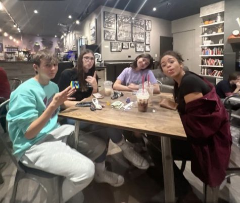 Ryan Hawt, Camryn Henderson, Gabby Gray, and Grace Swain sit at a table drinking coffee during Open Mic Night at Kave. They attend the event together most Thursdays.
