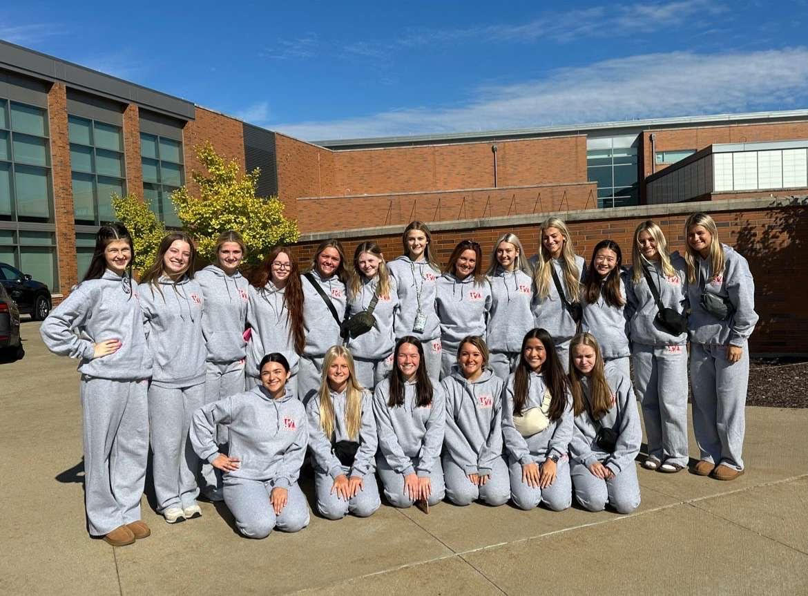 The cheer team poses for a picture as they get ready to load to depart from WHS. The team ended up cheering in their warm ups because of the weather. Photo Courtesy of Peggy Galata.