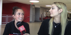 Reagan Rapp, an interviewer for the Wadsworth High School Broadcasting, talks with Ollie Smith, a senior, about what she does to get ready the day of homecoming for a segment of the announcements. The interviewers use the Bruin-Broadcasting logo on their microphones. Photo screenshotted from "Good Morning Grizzlies".
