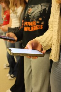 A student holds a phone in the hallway. With the new phone ban, this is not allowed. Photo by Riley Hunt. 