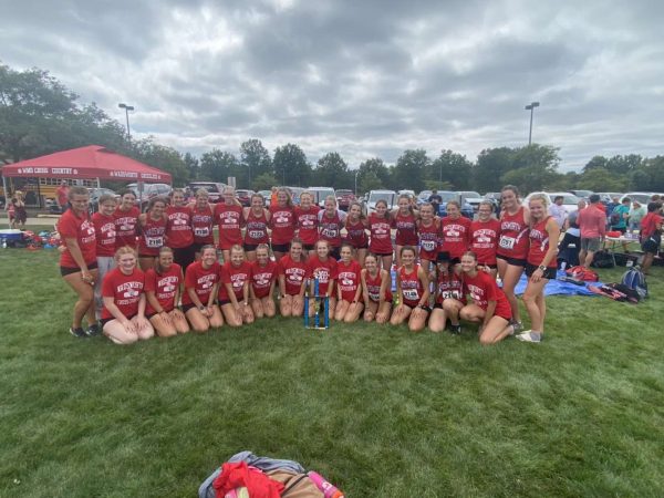 Wadsworth’s girls cross country team huddled together with a first-place trophy. The cross country race was in Wooster during 2023. Photo courtesy of Kailyn Biecker.
