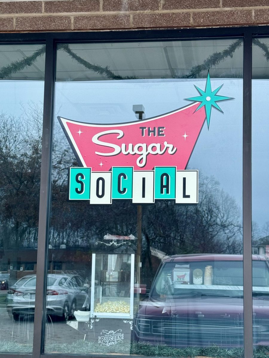 The Sugar Social logo is posted on the window outside the store. Sugar Socials is located on Great Oaks Trail. Photo by Grace Sharp. 