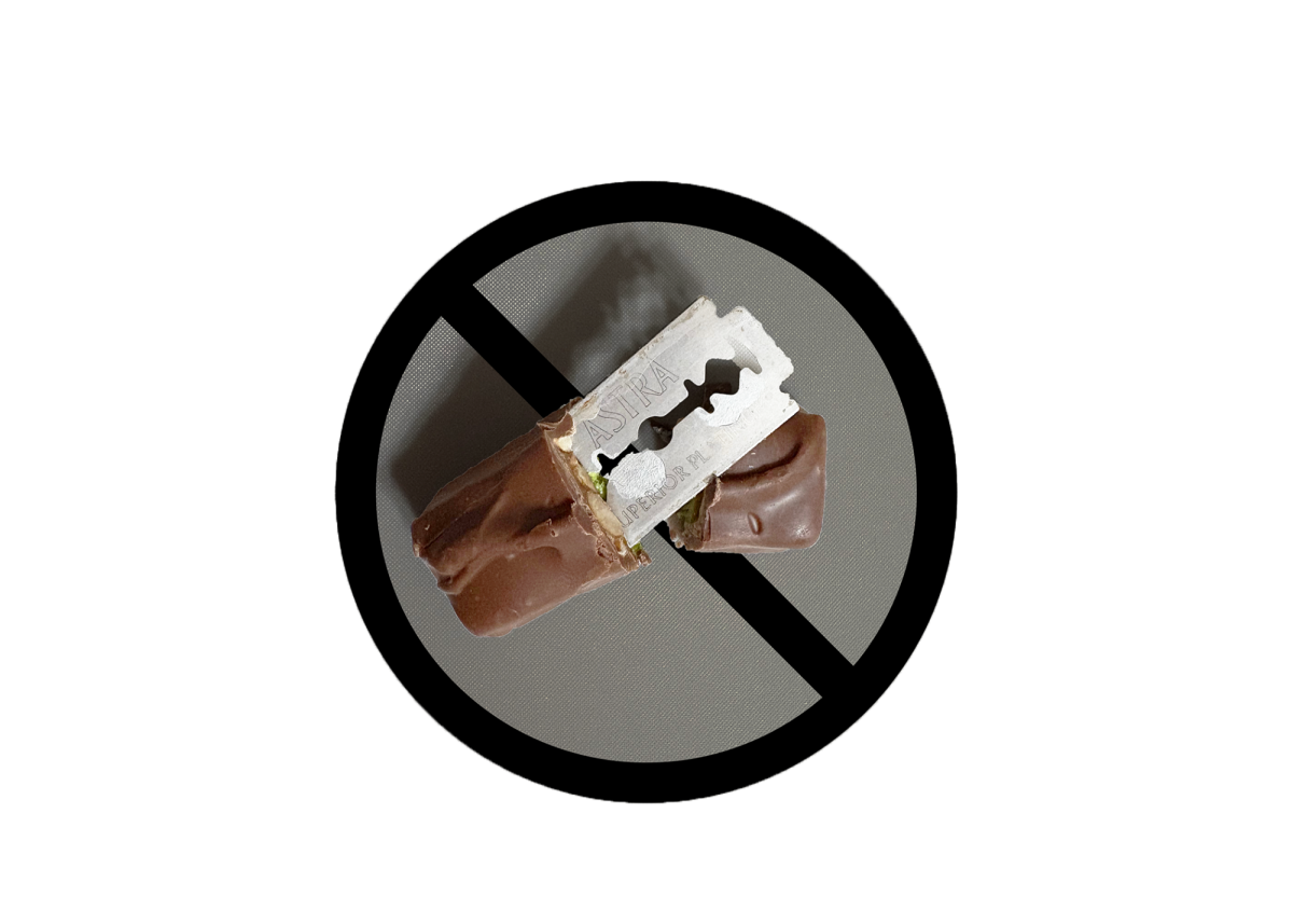 A prop image of a popular Halloween candy bar, a Snickers, with a razor blade sticking out of it. The prop was made to show one of the common examples of dangerous items that people claim can be found hidden within candy.