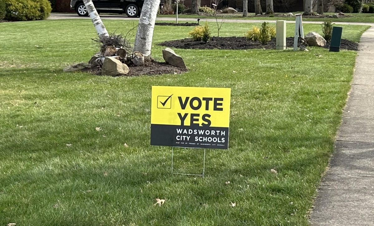A supporter of the new levy puts a yard sign that Friends of Wadsworth Schools have been giving out. Douglas Beeman gives out the yard sign to anyone who signs up for one.